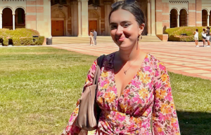Cognitive science Ph.D. student Morrow smiles at the camera while standing on a university campus lawn.