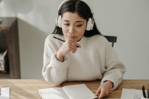 Person wearing headphones sitting at a desk while looking at a document.