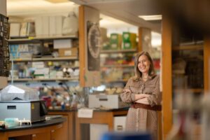 Dr. Hanna Mikkola stands in her laboratory workspace surrounded by equipment and shelves of supplies.