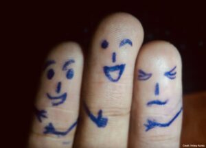 Three fingers with drawn faces displaying different emotions, representing friendship and social connection.