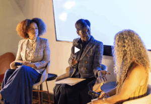 Three women leaders participate in a panel discussion about science and storytelling on stage.