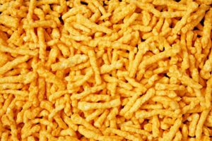 Close-up of crispy orange cheese-flavored puffed snacks scattered together