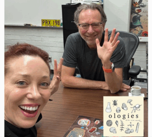 Dr. Daniel Blumstein and a colleague display an "Ologies" logo at a table during a marmotology podcast recording session.