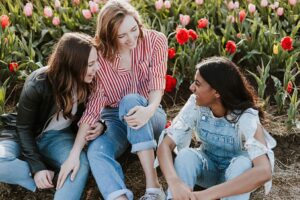 Three teens laughing together in a field of red and pink tulips.