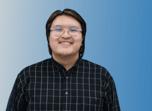 UCLA psychology student K.N. Ngo, winner of an NIH Undergraduate Scholarship, poses for a portrait against a blue background.