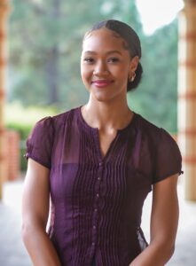 Portrait of a Bunche Fellow, a rising changemaker and scholar of Black life, wearing a purple button-up shirt