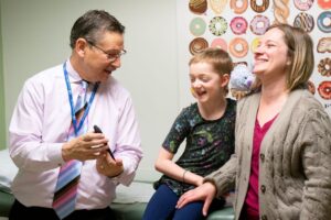 Dr. Donald Kohn speaks with a young patient and woman at UCLA about FDA-approved gene therapy for LAD-I