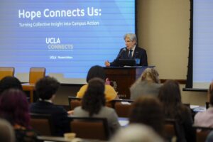 Chancellor Frenk at a podium during UCLA's "Hope Connects Us" mental health campaign event with audience members visible