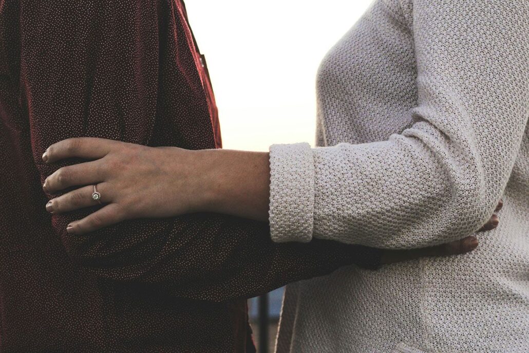 Two people touching arms in a supportive gesture during a counseling session.